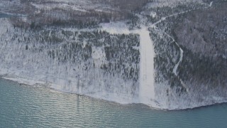 4K aerial stock footage approaching snow covered, wooded shore of Eklutna Lake, Alaska Aerial Stock Footage | AK0001_1357