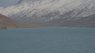 4K aerial stock footage surface of Eklutna Lake, snow covered, wooded hills, Chugach Mountains, Alaska Aerial Stock Footage | AK0001_1360