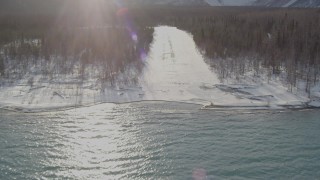 4K aerial stock footage flying over Eklutna Lake, descending toward snowy strip in woods, Alaska Aerial Stock Footage | AK0001_1361