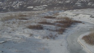 4K aerial stock footage flying over snow covered ground and shallow creek, Inner Lake George, Alaska Aerial Stock Footage | AK0001_1471