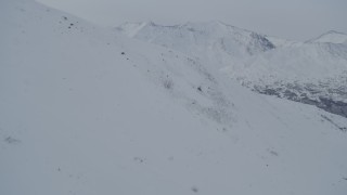 4K aerial stock footage flying over snowy slope toward mountain range, Chugach Mountains, Alaska Aerial Stock Footage | AK0001_1487