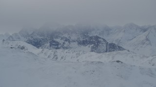 4K aerial stock footage the snow covered Chugach Mountains capped by low clouds, Alaska Aerial Stock Footage | AK0001_1492