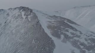 4K aerial stock footage flying toward and over a snow covered slope in the Chugach Mountains, Alaska Aerial Stock Footage | AK0001_1498