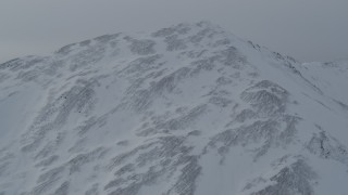 4K aerial stock footage flying up and over a snow covered mountain slope, Chugach Mountains, Alaska Aerial Stock Footage | AK0001_1499