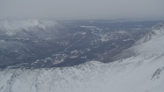 4K aerial stock footage the Eagle River Valley seen from snow covered Chugach Mountains, Alaska Aerial Stock Footage | AK0001_1503