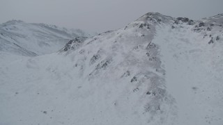 4K aerial stock footage flying over summit of snow covered mountain, Chugach Mountains, Alaska Aerial Stock Footage | AK0001_1506