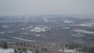 4K aerial stock footage flying away from wooded slope revealing Anchorage, Alaska in snow Aerial Stock Footage | AK0001_1511