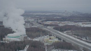 4K aerial stock footage flying by power plant toward Glenn Highway and shopping center in snow, Anchorage, Alaska Aerial Stock Footage | AK0001_1513