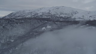 4K aerial stock footage flying through fog over snowy, wooded slopes in Chugach Mountains, Alaska Aerial Stock Footage | AK0001_1538