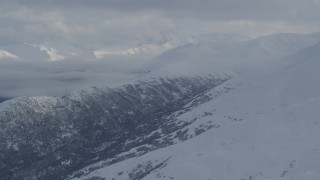 4K aerial stock footage the snowy Chugach Mountains, cloud covered Eklutna Lake Valley, Alaska Aerial Stock Footage | AK0001_1547