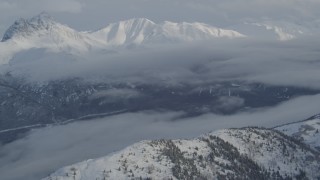 4K aerial stock footage clouds covering Eklutna Lake Valley, snowy Chugach Mountains, Alaska Aerial Stock Footage | AK0001_1549