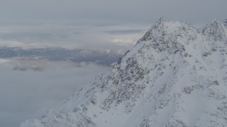 4K aerial stock footage low clouds covering Butte, snowy mountain peak, Chugach Mountains, Alaska Aerial Stock Footage | AK0001_1564