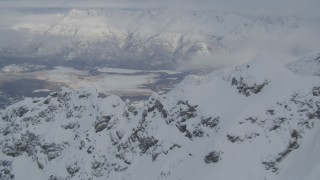 AK0001_1567 - 4K aerial stock footage flying over snowy mountain ridges toward Butte, Chugach Mountains, Alaska