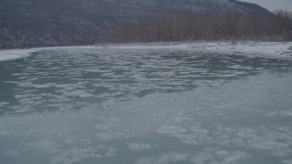 4K aerial stock footage flying low over icy river toward snow covered shore, Knik River Valley, Alaska Aerial Stock Footage | AK0001_1609