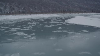 4K aerial stock footage flying low over icy river toward snow covered shore, Knik River Valley, Alaska Aerial Stock Footage | AK0001_1610