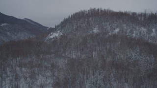 4K aerial stock footage flying over snow covered, wooded hill revealing Glenn Highway, Anchorage, Alaska Aerial Stock Footage | AK0001_1612