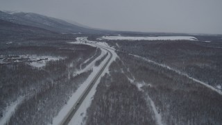 4K aerial stock footage snowy Glenn Highway stretching toward Chugach Mountains, Eagle River, Alaska Aerial Stock Footage | AK0001_1636