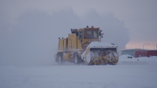 AK0001_1648 - 4K aerial stock footage passing a snow plow clearing Merrill Field at twilight, Anchorage, Alaska