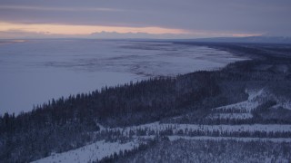 4K aerial stock footage following snowy, wooded shore of Point MacKenzie at twilight, Alaska Aerial Stock Footage | AK0001_1692