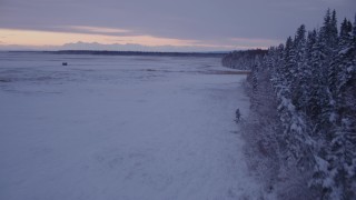 AK0001_1698 - 4K aerial stock footage flying low over frozen, snow covered ground at twilight, Point MacKenzie, Alaska