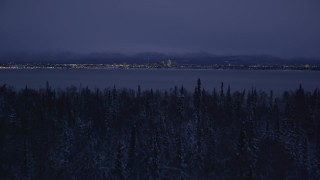 4K aerial stock footage ascend from snowy trees, reveal Downtown Anchorage, Alaska, night Aerial Stock Footage | AK0001_1718