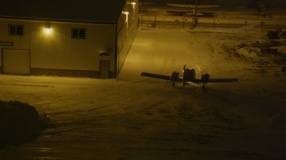 4K aerial stock footage an airplane rounding hanger at snowy Merrill Field, Anchorage, Alaska, night Aerial Stock Footage | AK0001_1738