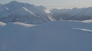 4K aerial stock footage fly over snowy ridge, reveal wooded valleys between Chugach Mountains, Alaska Aerial Stock Footage | AK0001_1745