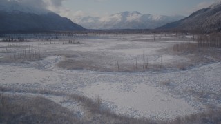 4K aerial stock footage flying over river and frozen, snowy ground toward Chugach Mountains, Alaska Aerial Stock Footage | AK0001_1771