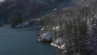 AK0001_1834 - 4K aerial stock footage flying along snowy, wooded shore, Port Wells, Alaska