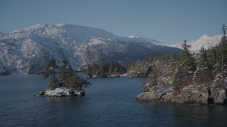 AK0001_1868 - 4K aerial stock footage flying between small, snowy island and mouth of Bettles Bay, Port Wells, Alaska