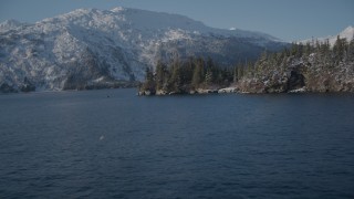 AK0001_1869 - 4K aerial stock footage flying toward snowy, wooded shore, then reveal Bettles Bay, Port Wells, Alaska