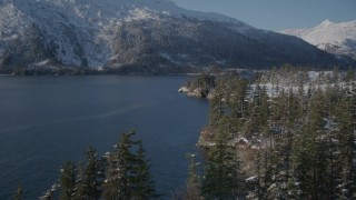 AK0001_1870 - 4K aerial stock footage flying along snowy shore, rounding it to reveal Bettles Bay, Port Wells, Alaska