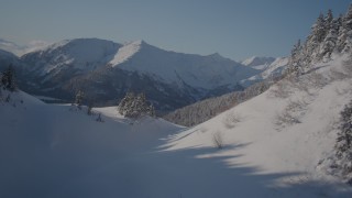 4K aerial stock footage flying over snowy ridge revealing forested river valley, Chugach Mountains, Alaska Aerial Stock Footage | AK0001_1890