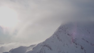 4K aerial stock footage flying by cloud, snow covered mountains summit, Chugach Mountains, Alaska Aerial Stock Footage | AK0001_1915