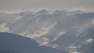 AK0001_1980 - 4K aerial stock footage snow covered, windblown Kenai Mountains and low clouds, Alaska