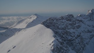 AK0001_1991 - 4K aerial stock footage flying over a snow covered mountain ridge in the Chugach Mountains, Alaska