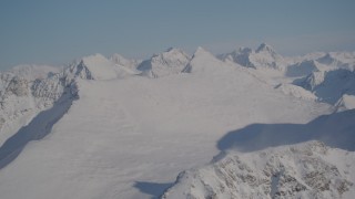 4K aerial stock footage flying by snowy, windblown mountain ranges in the Chugach Mountains, Alaska Aerial Stock Footage | AK0001_1995