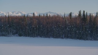 AK0001_2039 - 4K aerial stock footage cloudy Chugach Mountains, snowy wooded shore, Downtown Anchorage, Alaska