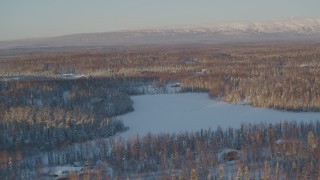 4K aerial stock footage houses near frozen lake, snowy forest in Knik-Fairview, Alaska, sunset Aerial Stock Footage | AK0001_2068