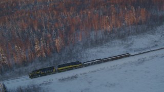 AK0001_2079 - 4K aerial stock footage tracking a train running by snowy trees at sunset, Wasilla, Alaska