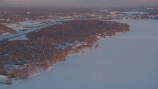 4K aerial stock footage fly over Lucile Lake, homes on the snowy shore, Wasilla, Alaska, sunset Aerial Stock Footage | AK0001_2083