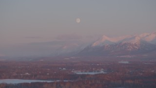 4K aerial stock footage the moon over the snow covered Chugach Mountains at twilight, Wasilla, Alaska Aerial Stock Footage | AK0001_2092