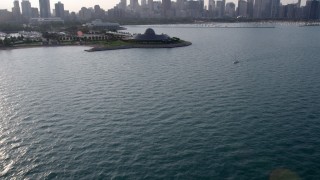 AX0001_099 - 4.8K aerial stock footage tilt from the lake to reveal Adler Planetarium and Downtown Chicago skyline, Illinois