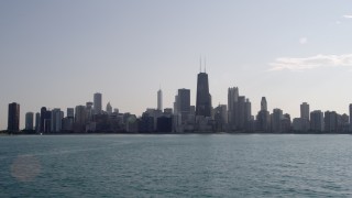 AX0002_019 - 4.8K aerial stock footage fly low over Lake Michigan and tilt to reveal the skyline of Downtown Chicago, Illinois