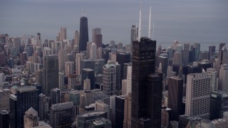 AX0003_044 - 4.8K aerial stock footage of flying near Willis Tower with a view across the cityscape to John Hancock Center at sunset, Downtown Chicago, Illinois