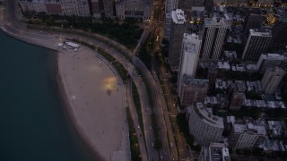 4.8K aerial stock footage tilt from Lake Shore Drive and up N Michigan Avenue, reveal the Drake Hotel and Downtown Chicago buildings, at twilight, Illinois Aerial Stock Footage | AX0003_096