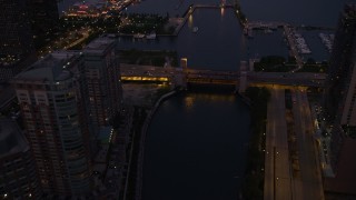 4.8K aerial stock footage of following Chicago River over a bridge at the mouth of the river, revealing Navy Pier, Downtown Illinois, twilight Aerial Stock Footage | AX0003_121