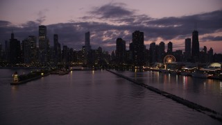 4.8K aerial stock footage of flying over Lake Michigan to approach Downtown Chicago skyline at twilight, Illinois Aerial Stock Footage | AX0003_129