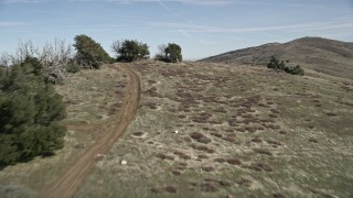 AX0005_055E - 5K aerial stock footage fly low over dirt roads and a mountain ridge in the Mojave Desert, California