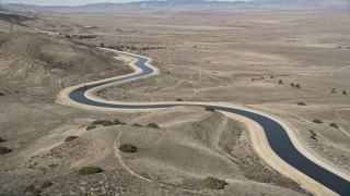 AX0005_059E - 5K aerial stock footage approach an aqueduct in the Mojave Desert of California